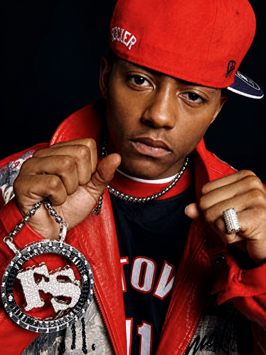 Cassidy wearing a red cap and jacket with a large pendant